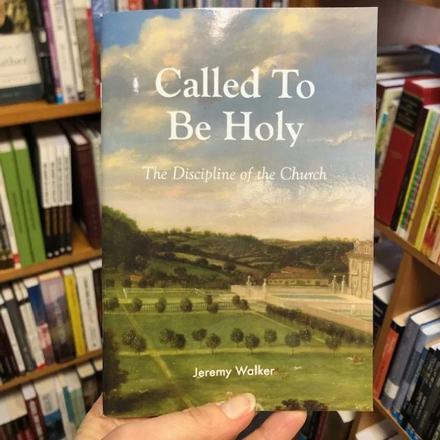 A hand holding a booklet infront of a book case